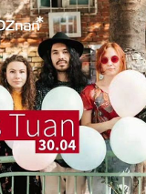 Czworo ludzi trzymający balony w rękach pozują na tle podówrka kamienicy.