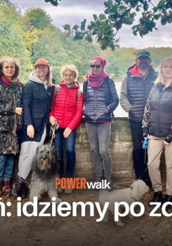 Grupa ludzi pozująca do zdjęcia z kilkoma psami. W tle drzewa oraz jezioro. Na froncie tytuł wydarzenia "Power walk" i hasło: "Poznań: idziemy po zdrowie!"