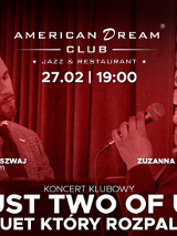 Plakat koncertowy utrzymany w głębokiej, czerwonej tonacji. Przedstawia dwoje artystów: po lewej stronie mężczyzna w garniturze grający na fortepianie z lekko pochyloną głową, po prawej uśmiechnięta kobieta w okularach śpiewająca do mikrofonu. W tle widać ciemną kurtynę, co podkreśla klubowy klimat wydarzenia. Wokół widać białe napisy, są to szczegóły na temat wydarzenia zawarte w treści artykułu.