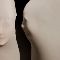 Grafika przedstawiająca dwie jasne płaszczyzny, jedna z zarysem twarzy; między płaszczyznami czarny pas.