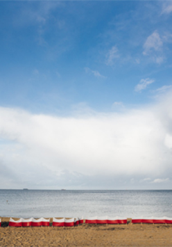 Plaża - obraz niebo, morze i piaszczysta plaża.Na plaży biało-czerwone parawany.