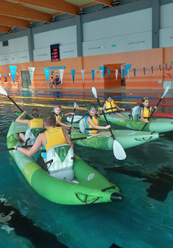 Sześcioro uczestników zajęć w trzech kajakach na basenie.