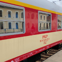 Biało-beżowy wagon starego składu pociagow PKP. Ma duże okna. Stoi na peronie.