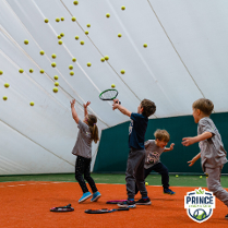 Czworo dzieci bawi się piłkami do tenisa.