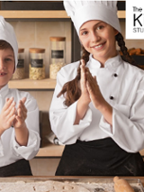 Dwoje dzieci w strojach kucharza w kuchni. Logo studia kulinarnego.