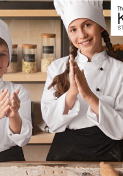 Dwoje dzieci w strojach kucharza w kuchni. Logo studia kulinarnego.