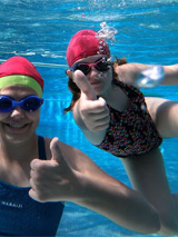 Dziewczynki z kciukiem uniesionym w górę, w basenie.