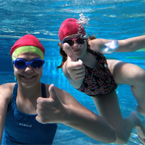 Dziewczynki z kciukiem uniesionym w górę, w basenie.