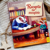 Zdjęcie przedstawia okładkę książki. Znajduje się na niej borsuk stojący z kontuarem, przyodziany w okulary i płaszcz.