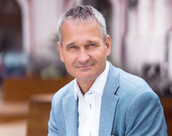 Portret mężczyzny w jasnoniebieskim garniturze.