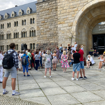 Grupa ludzi stoi pod wejściem do Kina Pałacowego w poznańskim Zamku Cesarskim.