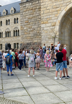 Grupa ludzi stoi pod wejściem do Kina Pałacowego w poznańskim Zamku Cesarskim.