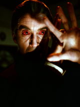 Na fotografii widoczna jest postać, która wygląda przerażająco lub mrocznie. Może to być scena z filmu grozy lub thrillera. Postać ma czerwone oczy, co może być wynikiem użycia specjalnych soczewek kontaktowych, mających na celu stworzenie efektu nadprzyrodzonego lub mistycznego spojrzenia. Oświetlenie i ogólny ton obrazu tworzą atmosferę napięcia i niepokoju, co jest charakterystyczne dla filmów grozy.