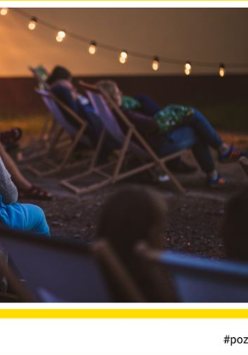 Kino plenerowe z leżakami i podwieszonymi lampkami, z boku napisy, które informują o wydarzeniu.