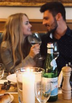 Para osób siedzi przy zastanawionym stole w romatycznej atmosferze.