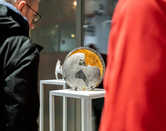 Rzeźba o kształcie okręgu, ze stali i złota, ze znakami symbolicznymi misji Voyager