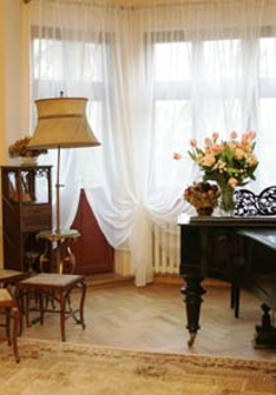 Salon: fortepian, krzesła, lampa