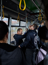 Dwóch mężczyzn prezentuje jak samoobronić się w tramwaju. pokazowi przyglądają się uczestnicy.