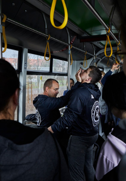 Dwóch mężczyzn prezentuje jak samoobronić się w tramwaju. pokazowi przyglądają się uczestnicy.