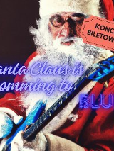 Mężczyzna w stroju Mikołaja trzyma w ręku gitarę. Przez środek grafiki przechodzi niebieski napis "Santa Claus is Coming to Blues".