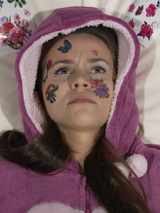 Zdjęcie leżącej dziewczyny z kolorowymi tatuażami na twarzy