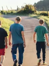 Kadr z filmu "Niech to diabli", cztery osoby, zwrócone do widza plecami idą wiejską drogą.