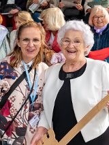 Zdjęcie przedstawia szczęśliwą emerytkę trzymającą metrowy klucz do Poznania. W tle siedzą inni emeryci.