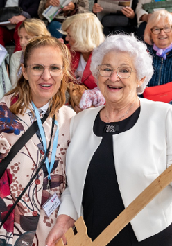 Zdjęcie przedstawia szczęśliwą emerytkę trzymającą metrowy klucz do Poznania. W tle siedzą inni emeryci.