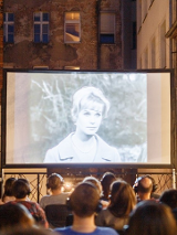 Taras kina Muza a na nim seans silent cinema. Przed widownią ekran z wyswietlanym filmem, widzowie w słuchawkach.