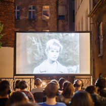 Taras kina Muza a na nim seans silent cinema. Przed widownią ekran z wyswietlanym filmem, widzowie w słuchawkach.