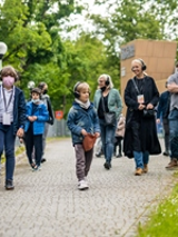 Zdjęcie przedstawiające grupę spacerujących ludzi ze słuchawkami na uszach.