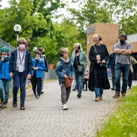 Zdjęcie przedstawiające grupę spacerujących ludzi ze słuchawkami na uszach.