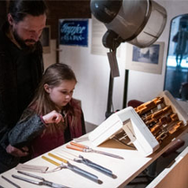 Dziewczynka najprawdopodobniej z ojcem ogląda narzędzie (np: dłuta)