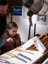 Dziewczynka najprawdopodobniej z ojcem ogląda narzędzie (np: dłuta)