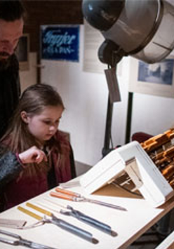 Dziewczynka najprawdopodobniej z ojcem ogląda narzędzie (np: dłuta)