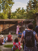 Tłum słucha kobiety grającej na skrzypcach na kameralnym podwórku domu.