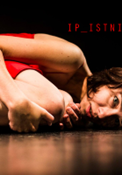 Zdjęcie ze spektaklu - kobieta w czerwonej sukience leży skulona na podłodze.