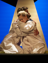 Zdjęcie ze spektaklu - kobieta i mężczyzna siedząc przytulają się do siebie.