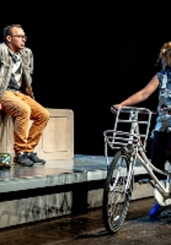 Scena ze spektaklu - dziewczyna na rowerze i chłopak siedzacy na murku.