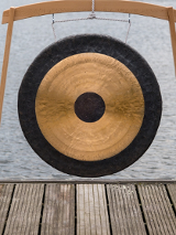 Gong podwieszony na drewnianym stelażu, który ustawiono na drewnianym pomoście.