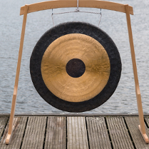 Gong podwieszony na drewnianym stelażu, który ustawiono na drewnianym pomoście.