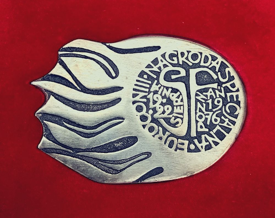 Srebrna odznaka przypominająca kształtem kometę.