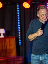 Mężczyzna występuje na scenie, trzyma mikrofon w ręku.