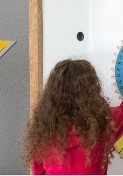 Dziewczynka rozwiazuje szyfr przy pomocy koła zębatego z literami przy trybach.
