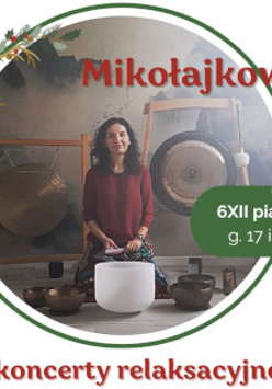 Zdjęcie przedstawia kobietę siedzącą przed dużym gongiem oraz kilkoma misami do śpiewu. Kobieta ma na sobie czerwoną koszulkę. Gong jest zawieszony na suficie za kobietą. Misy do śpiewu są ułożone w półkolu przed nią. Tło stanowi biała ściana. Kobieta ma ciemne włosy i patrzy w obiektyw aparatu. Kobieta lekko się uśmiecha.