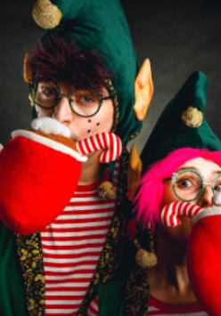 Dwoje aktorów w strojach elfów z dużymi pluszowymi, czerwonymi kubkami.