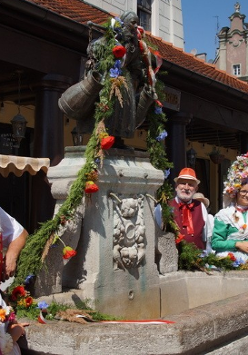 Foto. Przy udekorowanej girlandą fontannie Bamberki pięć postaci w strojach bamberskich.