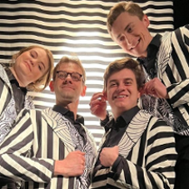 Zdjęcie aktorów we frakach w biało-czarne pasy.