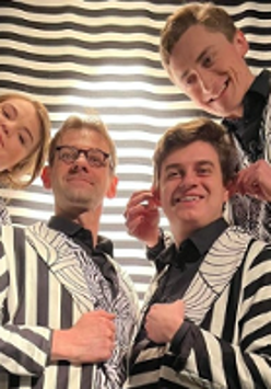 Zdjęcie aktorów we frakach w biało-czarne pasy.