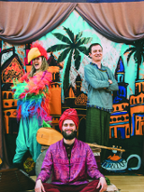 Osoby w orientalnych strojach na scenie teatralnej.